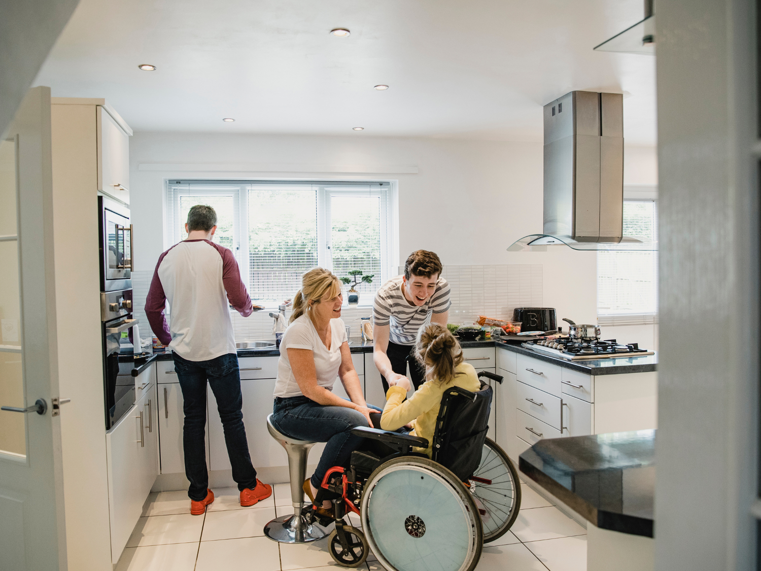 A family in a kitchen, with a woman in a wheelchair, preparing a meal together.